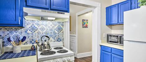 A kitchen with blue cabinets, a white stove, and a microwave.