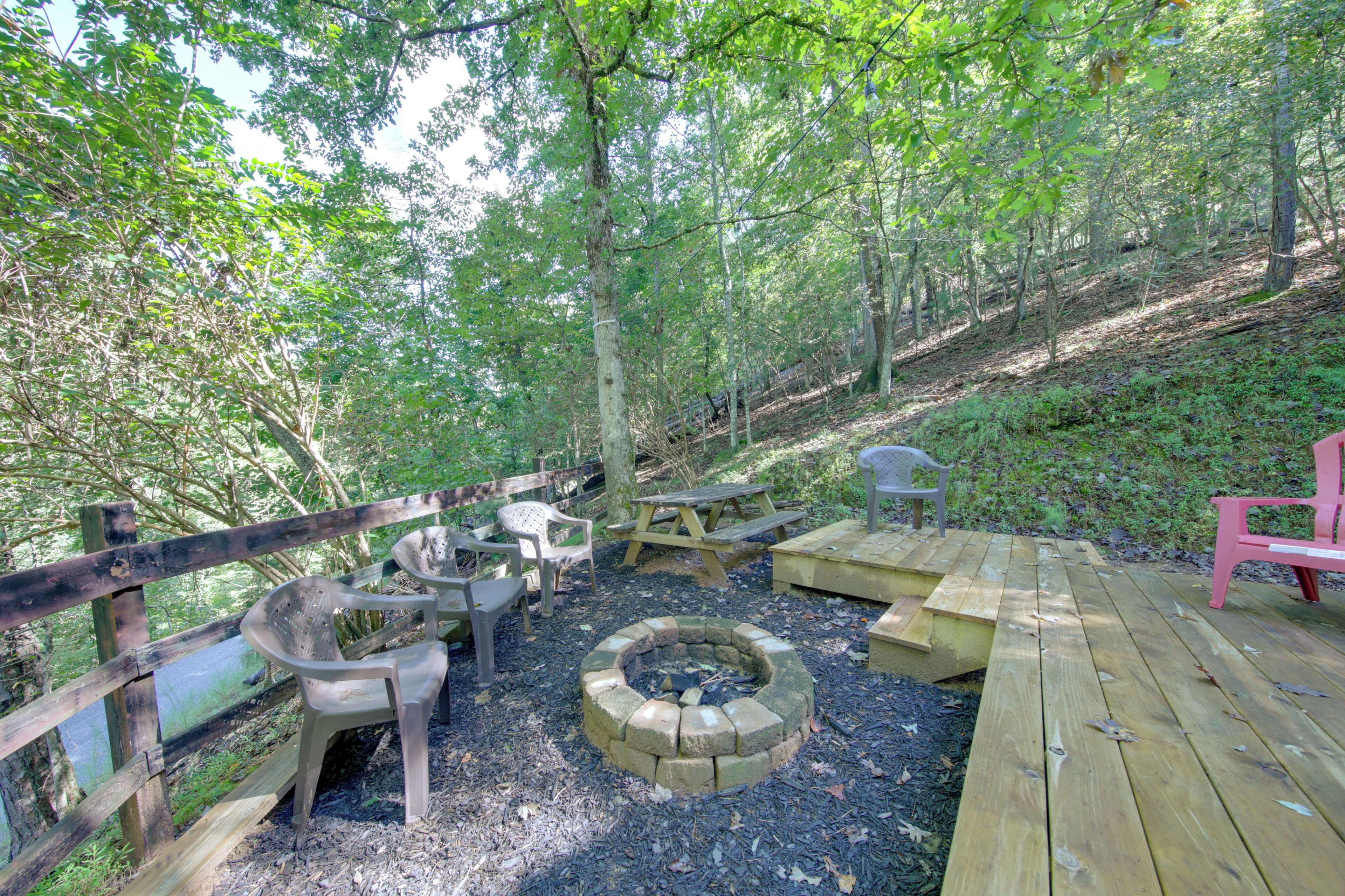 A wooden deck with picnic tables and chairs, surrounded by trees.