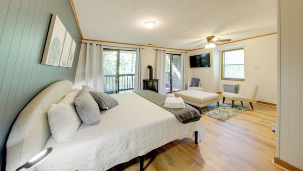 A bedroom with a bed, a chair, a small table, and a ceiling fan. - Pet-friendly Ellijay Cabin in the Woods on 1 Acre! (Ellijay)