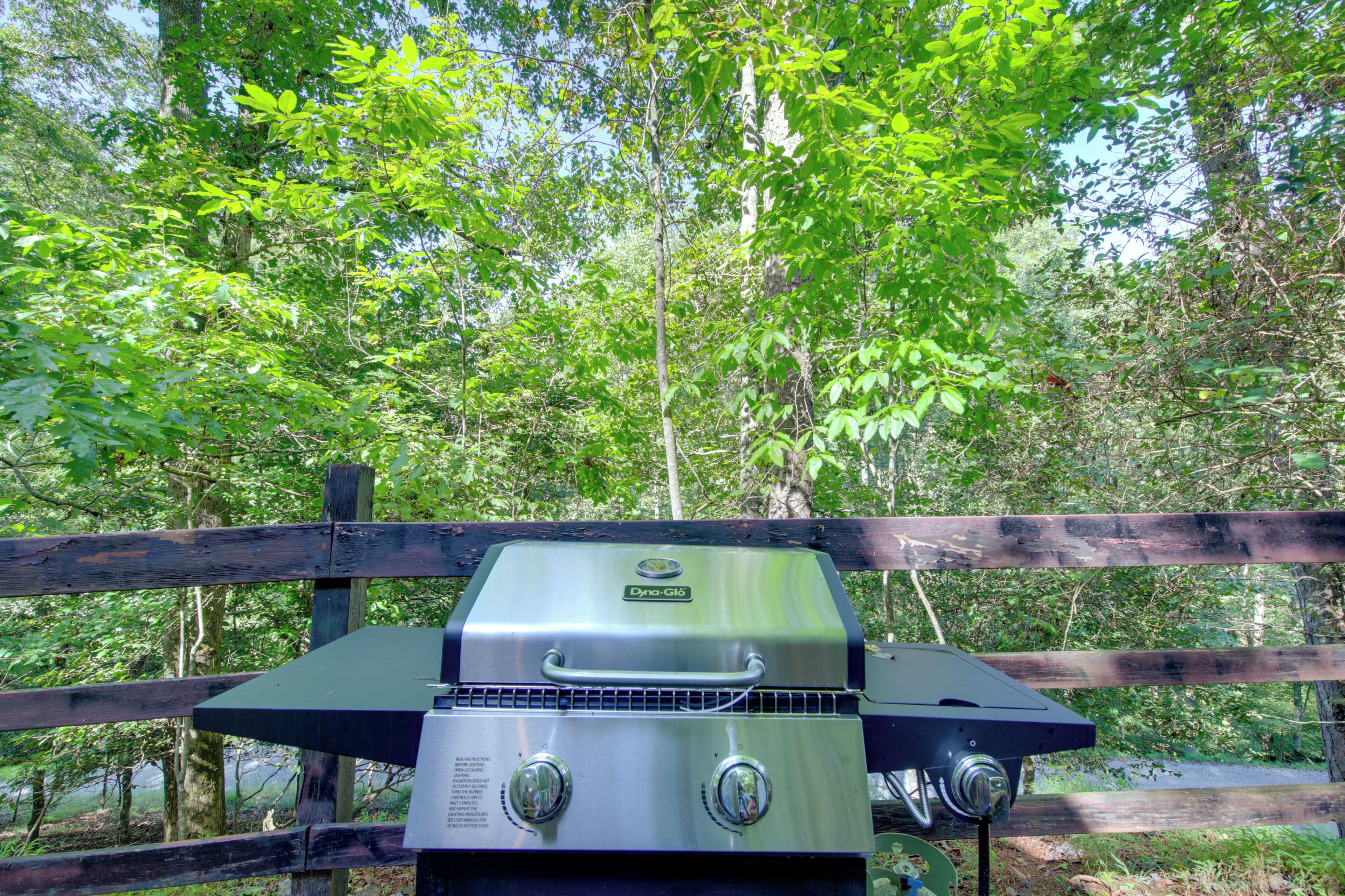 A portable grill with a digital display, set against a backdrop of a wooden fence and lush greenery.