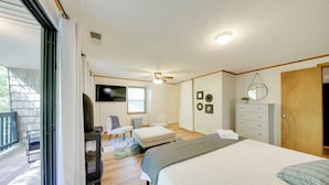 A bedroom with a large bed, a dresser, a chair, a small table, and a television. - Pet-friendly Ellijay Cabin in the Woods on 1 Acre! (Ellijay)