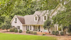 A two-story house with a covered porch, surrounded by a well-maintained lawn and trees. - Family-friendly Athens Escape ~ 2 Mi to Uga! (Athens)