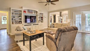 A spacious living room with a large TV, comfortable seating, and built-in shelving. - Family-friendly Athens Escape ~ 2 Mi to Uga! (Athens)
