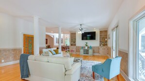 A spacious living room with a white sofa, a blue armchair, and a flat-screen TV mounted on the wall. - Spacious Georgia Vacation Rental w/ Large Deck (Leesburg)