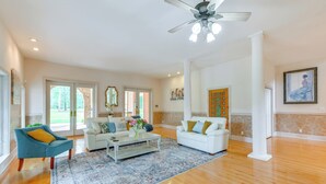 A spacious living room with hardwood flooring, a ceiling fan, and two white sofas with decorative pillows. - Spacious Georgia Vacation Rental w/ Large Deck (Leesburg)