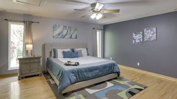 Une chambre à coucher avec un lit, une table de chevet, un ventilateur de plafond et des œuvres d’art accrochées aux murs.