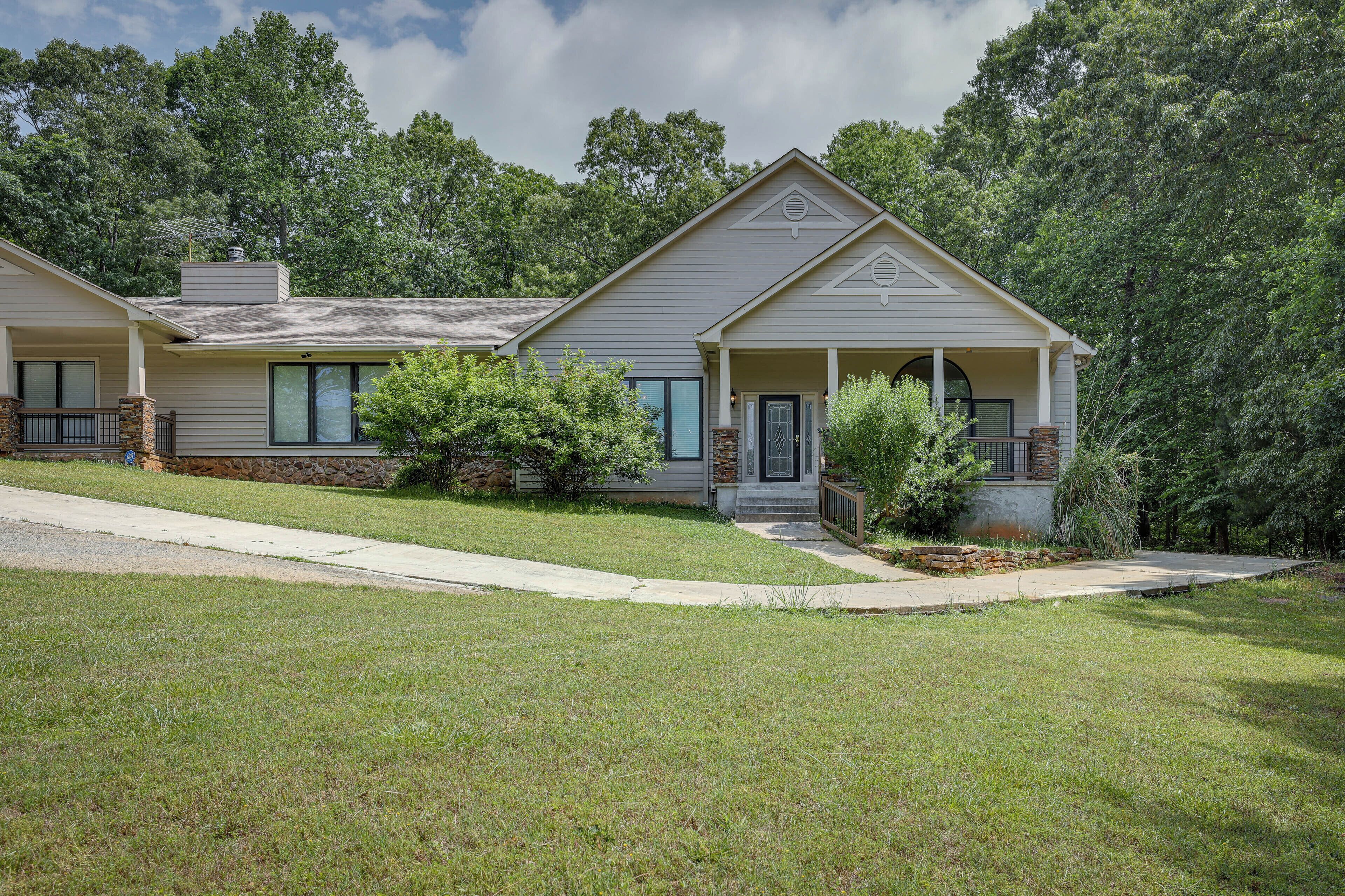 A two-story house with a front porch, a stone foundation, and a well-maintained lawn.