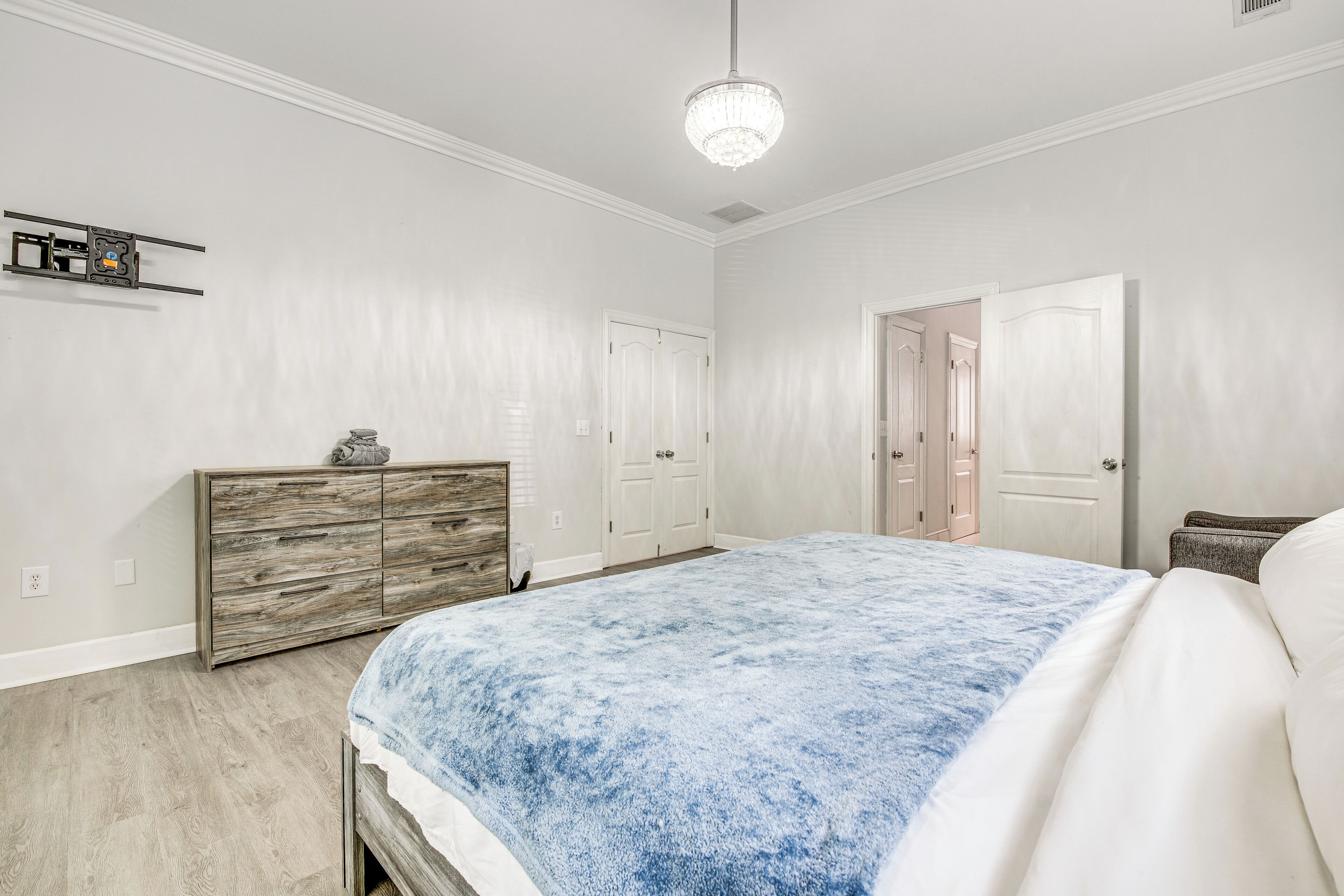 Un dormitorio con cama, cómoda y dos puertas.