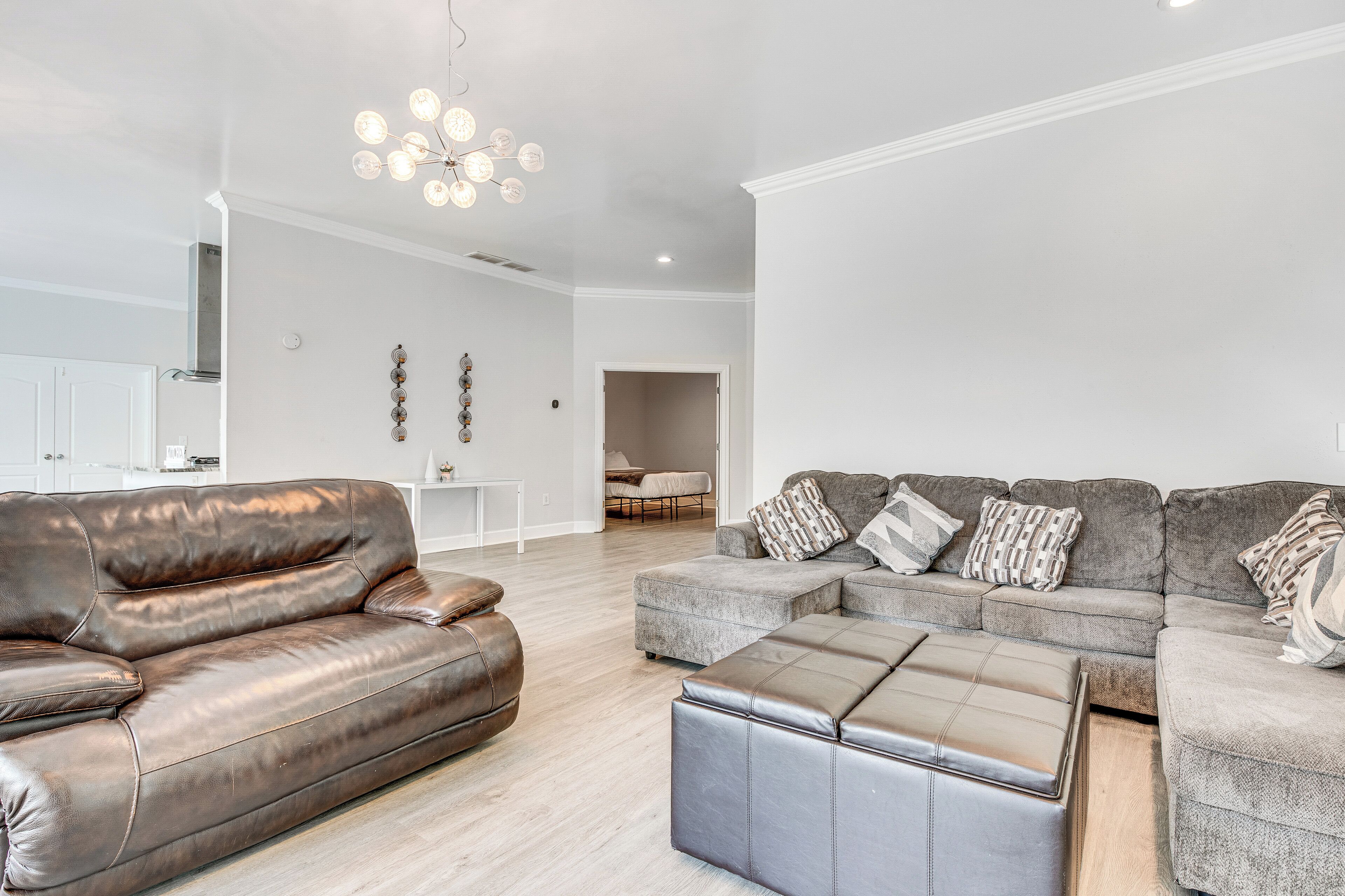 A modern living room with a brown leather sofa, grey sectional, and ottoman.
