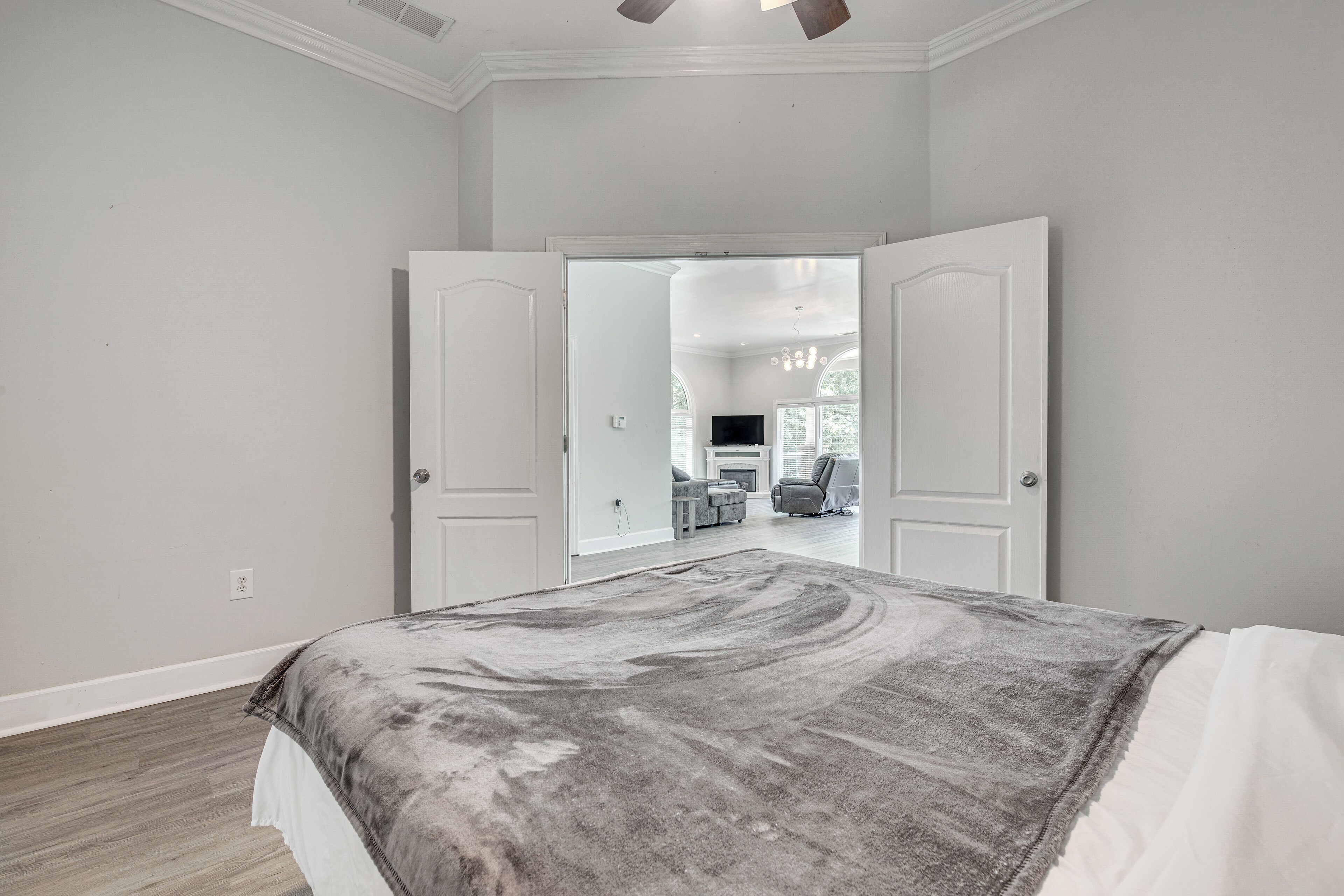 Une chambre avec un grand lit, une porte donnant sur un espace de vie et une vue sur le salon à travers cette porte.