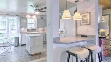 A modern kitchen with a central island, pendant lighting, and a dining area with bar stools.