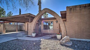 A building with a brick exterior, a covered patio area, and a gravel driveway. - Eastside Home w/ Pool Near Hiking! (Tucson)