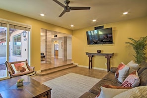 A spacious living room with a brown leather sofa, a coffee table, and a TV mounted on the wall.