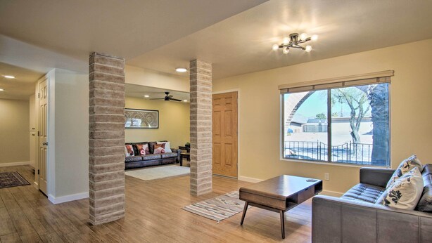 A spacious living room with hardwood floors, a large window, and a fireplace. - Eastside Home w/ Pool Near Hiking! (Tucson)
