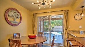 A dining area with a wooden table, chairs, a red bowl, and a wall clock. - Eastside Home w/ Pool Near Hiking! (Tucson)