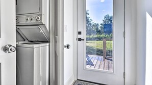 Une cuisine compacte dotée d’un four encastré et d’une porte donnant sur une terrasse avec une rambarde en bois.