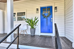 A blue door with a wreath, a potted plant, and white chairs on a wooden porch. - Chic St Marys Home, 2 Blocks From Riverfront (St. Marys)