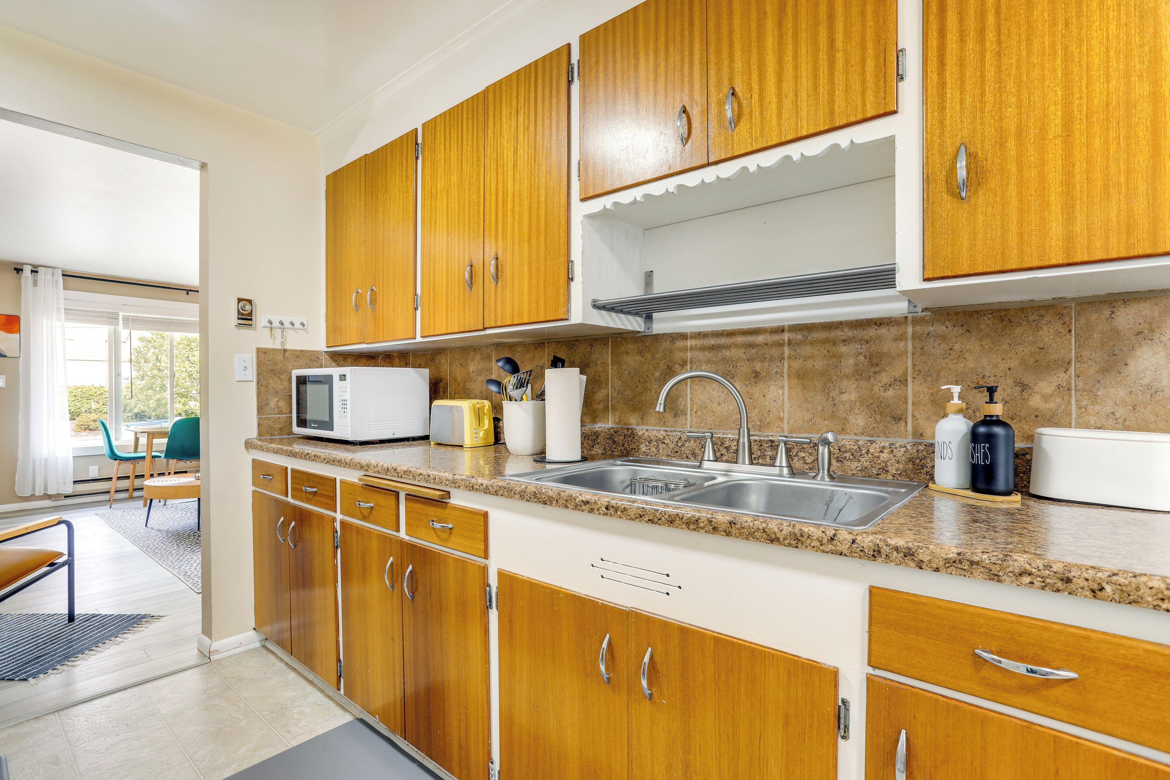 Una cocina moderna con armarios de madera, encimera de granito, microondas, fregadero y tostadora.
