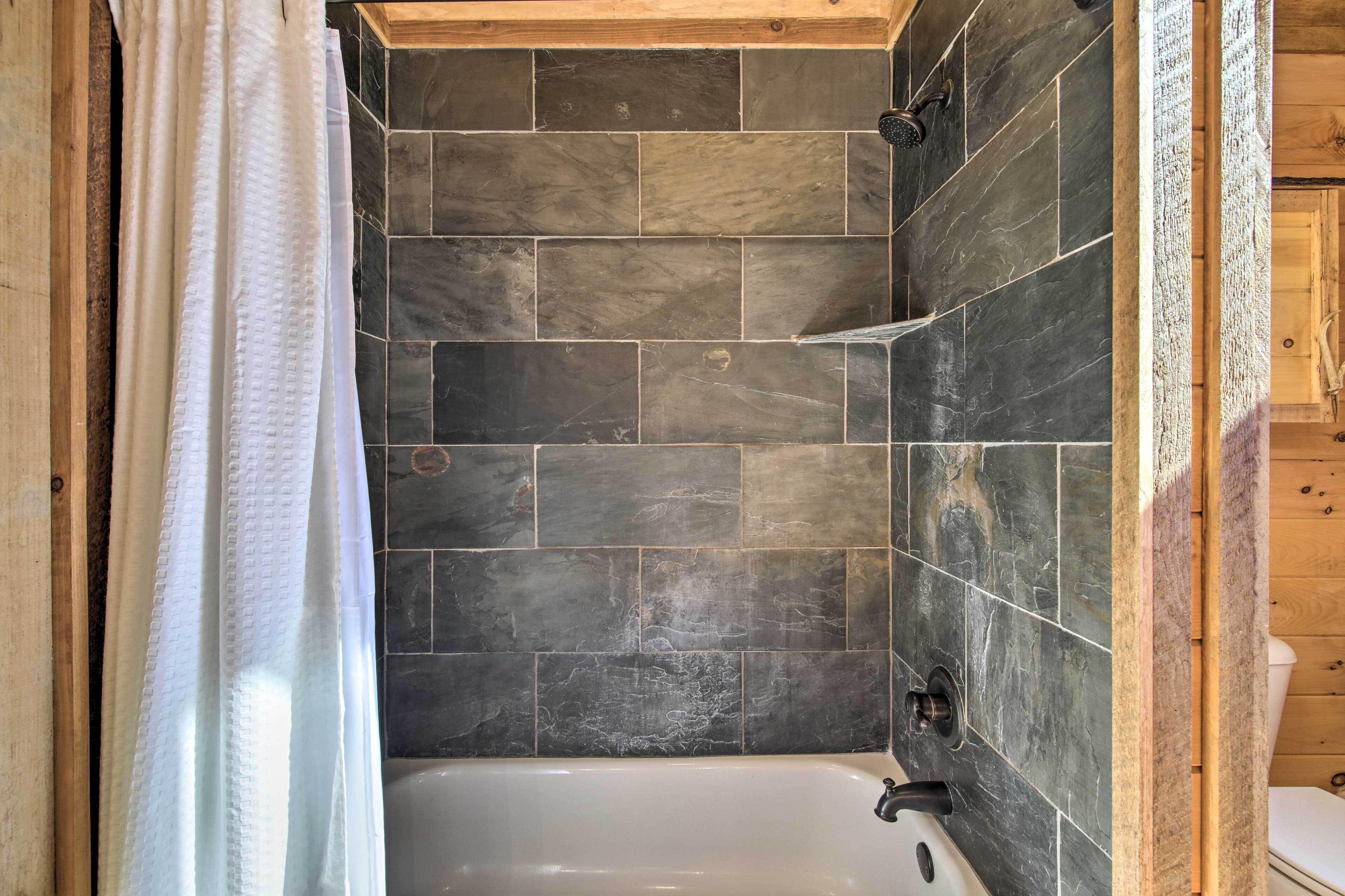 A bathroom with a bathtub, tiled walls, and wooden ceiling beams.