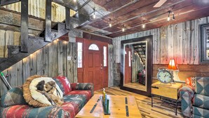 Ein rustikaler Innenraum mit einer Holztreppe, einer roten Tür und einem Sofa mit Felldecke.