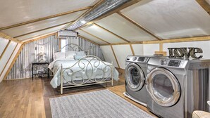 Ein Schlafzimmer mit Bett, Waschmaschine und einem kleinen Tisch mit Lampe.
