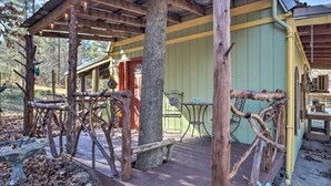 Ein rustikales Holzgebäude mit überdachter Veranda, einer Bank und einem Vogelhäuschen.