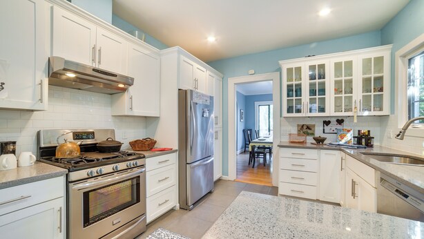 A modern kitchen with stainless steel appliances, white cabinetry, and a granite countertop. - Historic Seattle Vacation Rental in Seward Park! (Seattle)