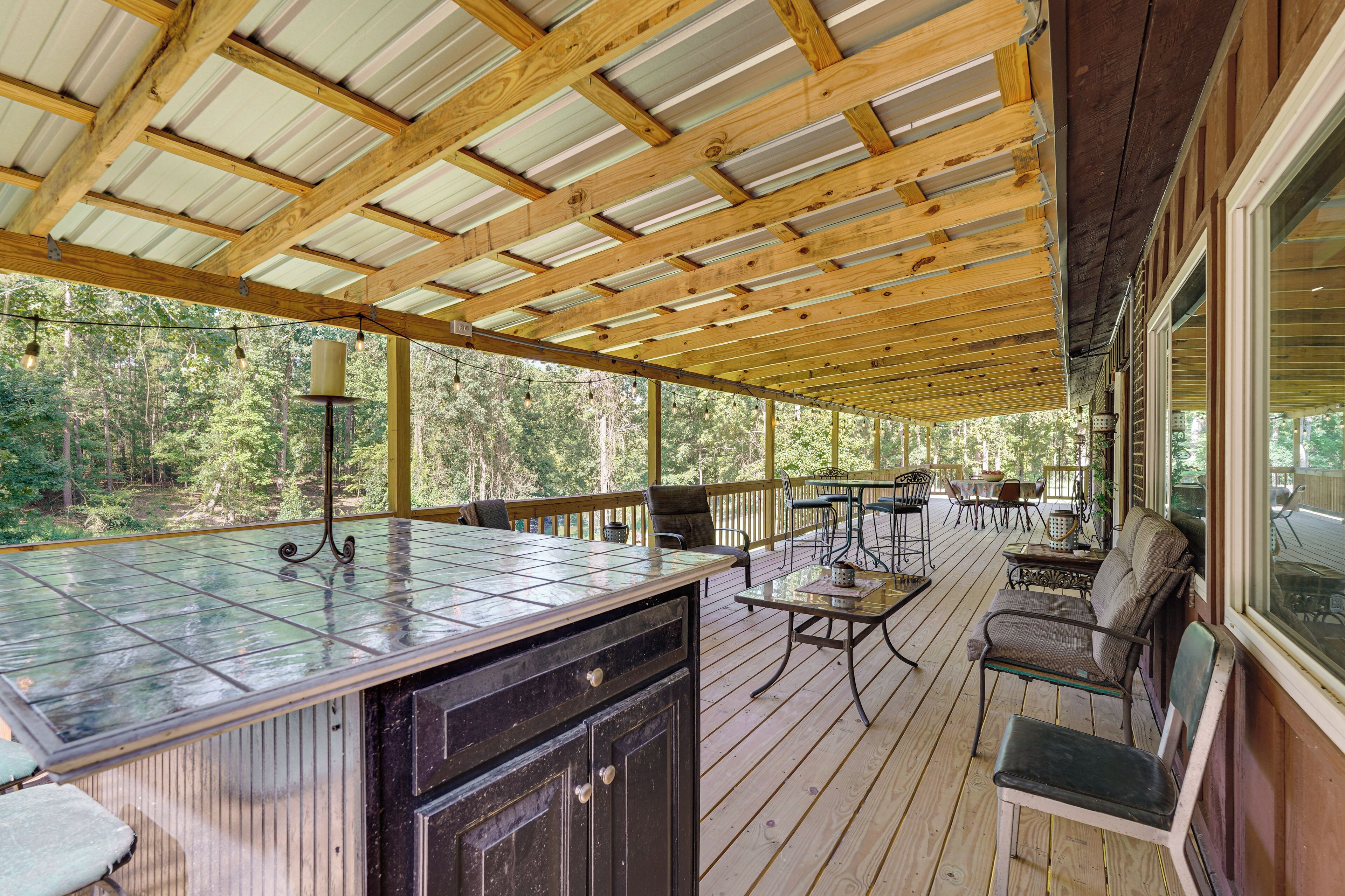 A covered outdoor deck with a bar area, seating, and a view of the forest.