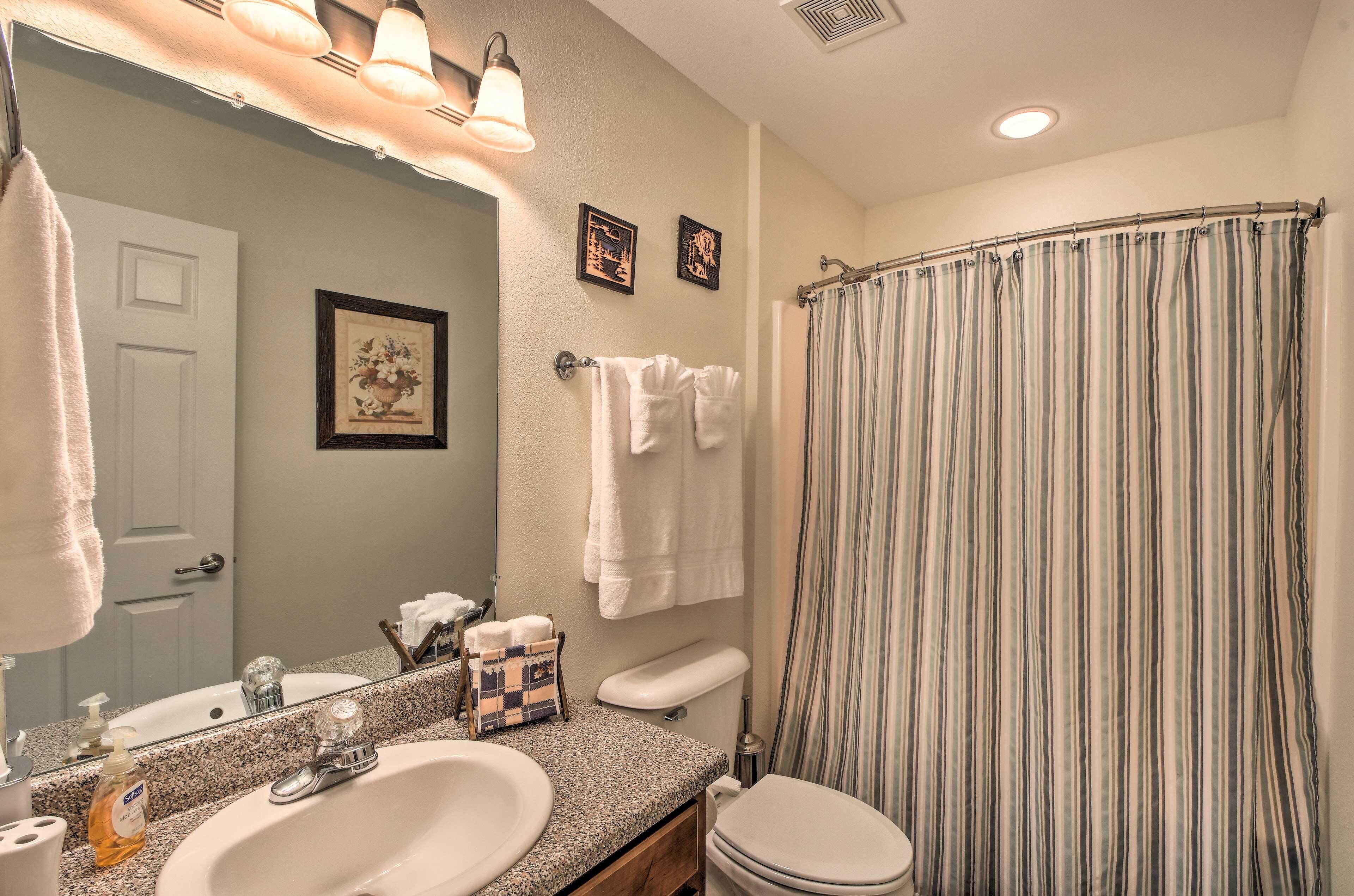 A bathroom with a sink, mirror, towel rack, and striped shower curtain.