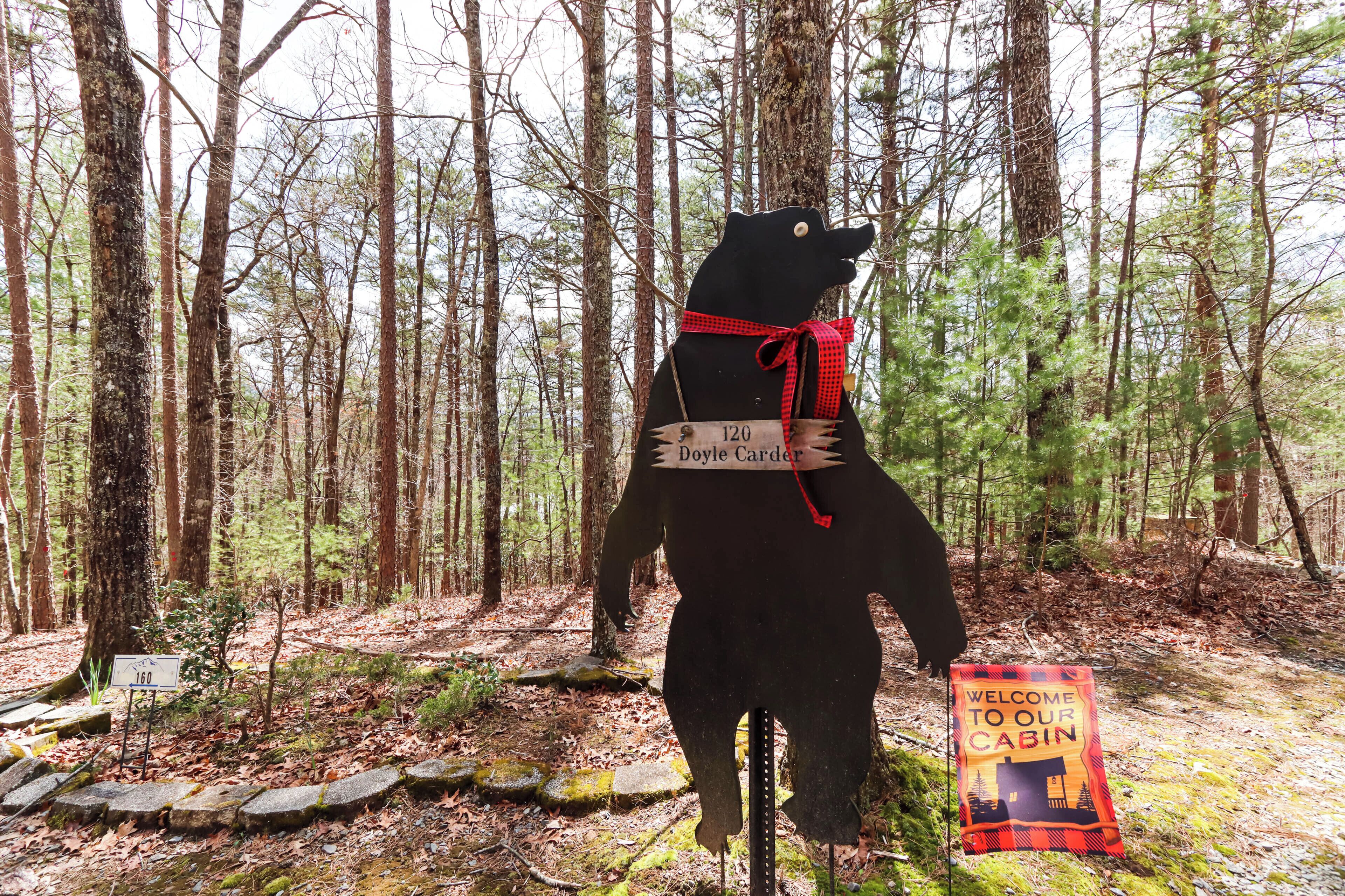 A bear statue with a sign reading "Doyle Corder" and a welcome sign to a cabin.