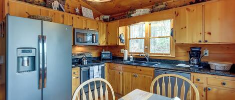 A cabin-style kitchen with wooden cabinets, a refrigerator, microwave, and a sink.