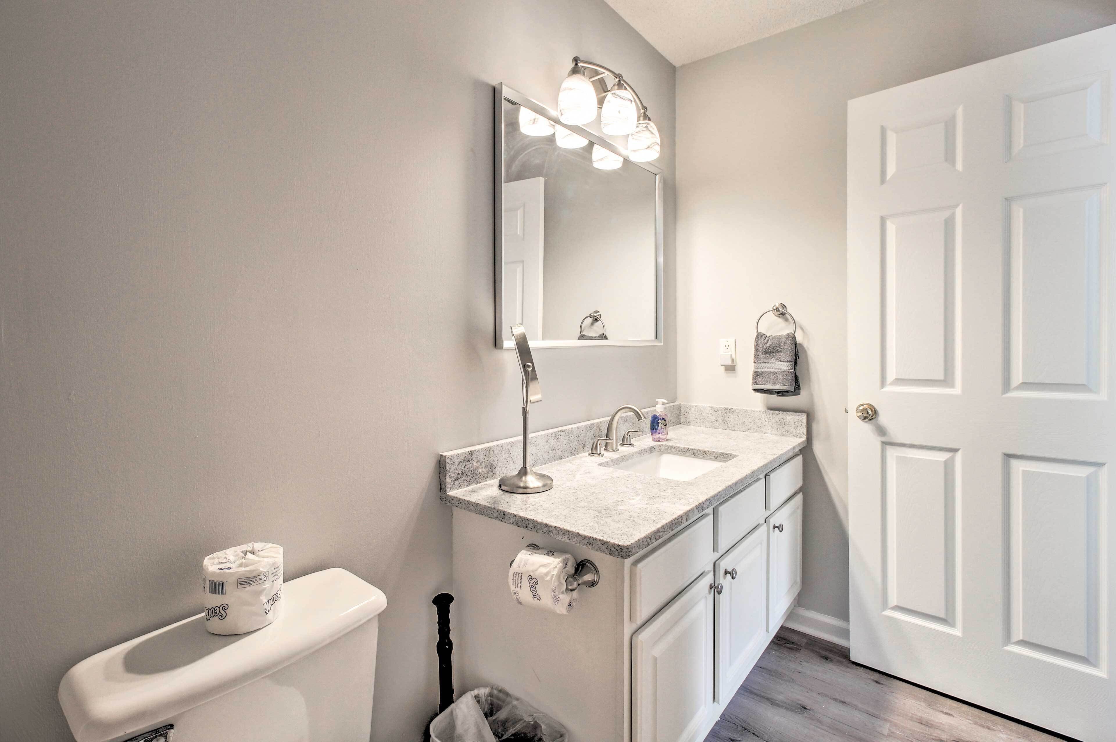 A bathroom with a toilet, sink, mirror, and a door.