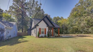 Une maison de plain-pied avec un toit à pignon, un porche à l’avant et un petit jardin devant.