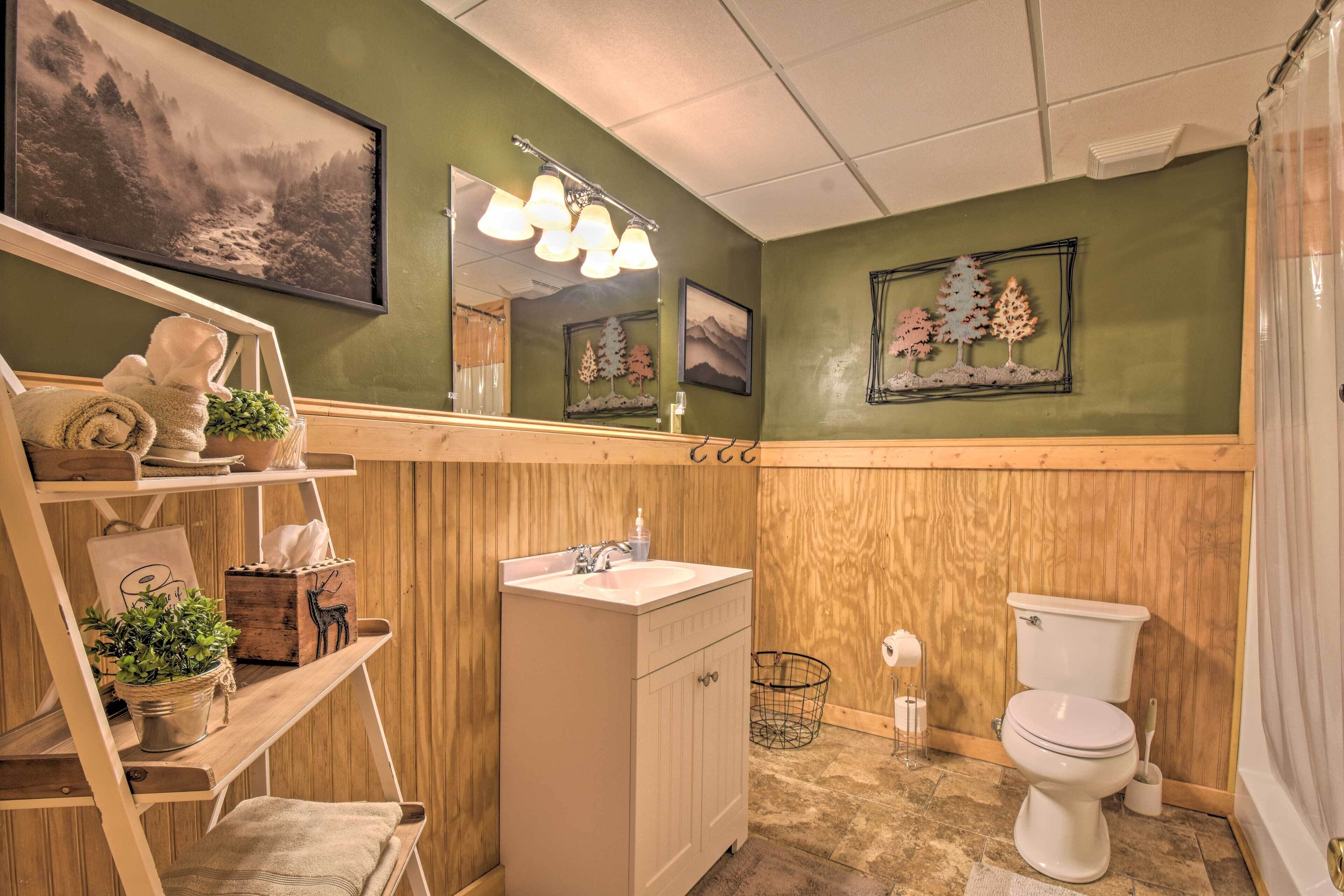 A bathroom with a wooden vanity, a sink, a toilet, and a shelf with plants.