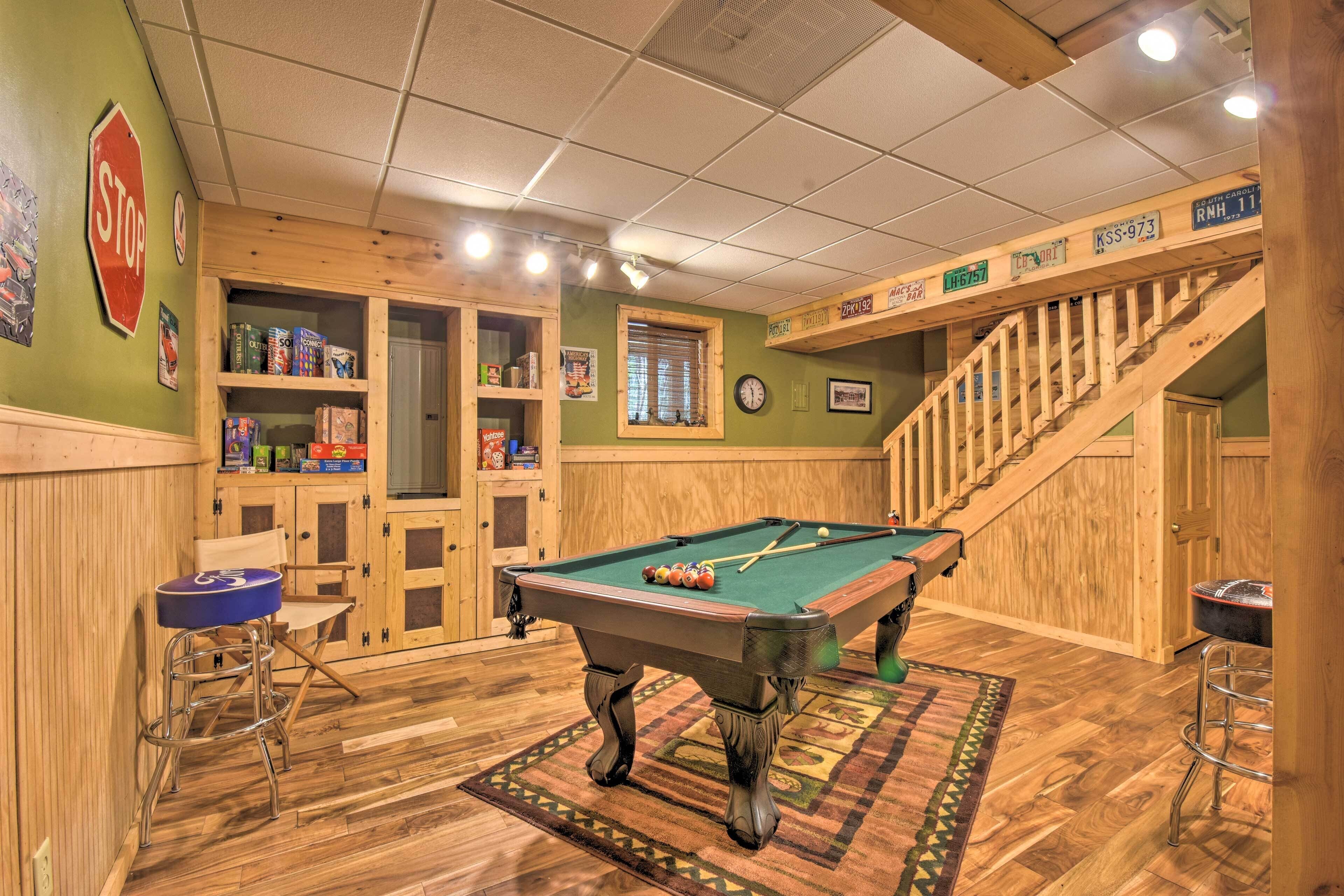 A pool table in a room with wooden walls and a staircase.