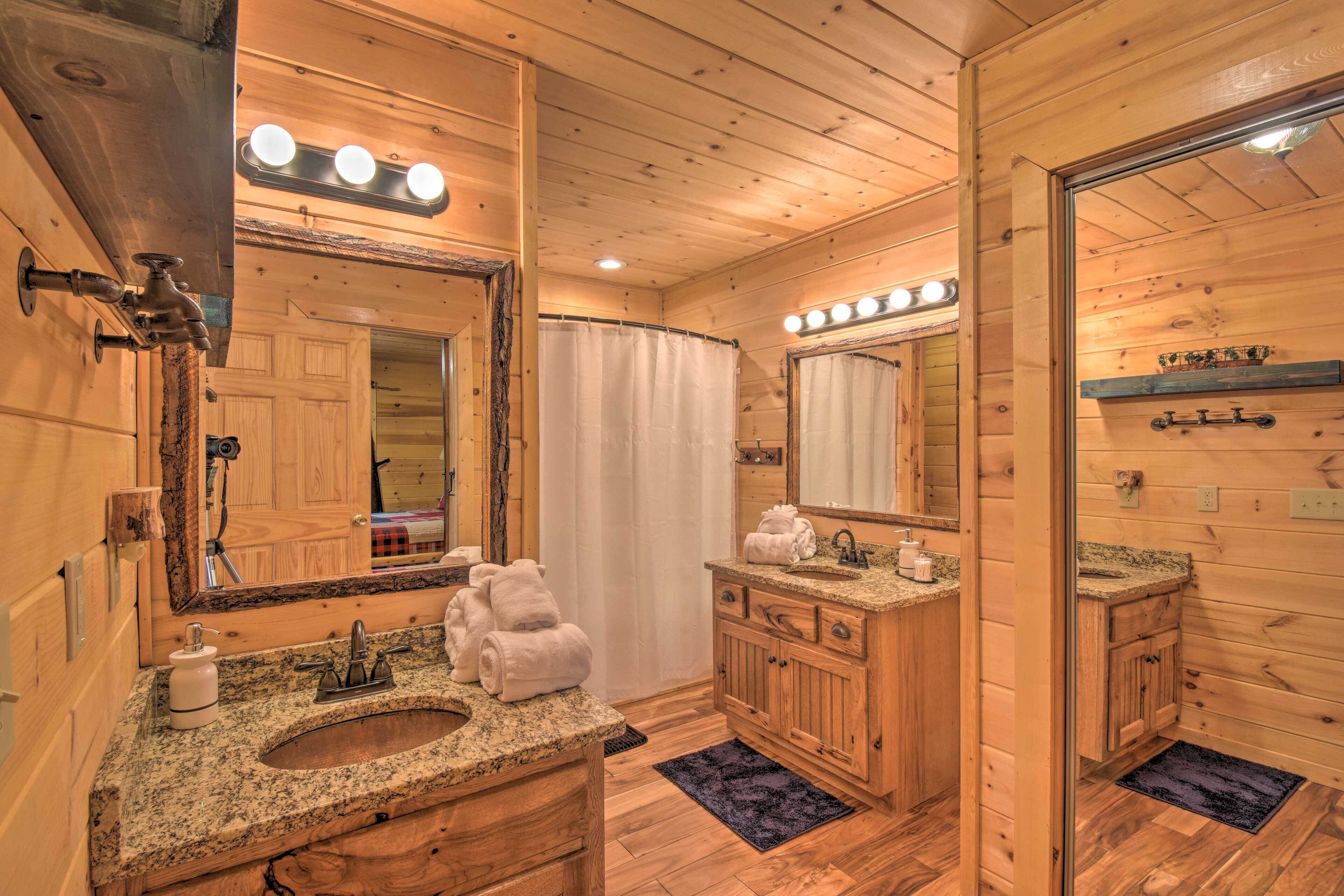 Une salle de bain rustique, avec une cabine en bois, un lavabo, un meuble-lavabo et un grand miroir.