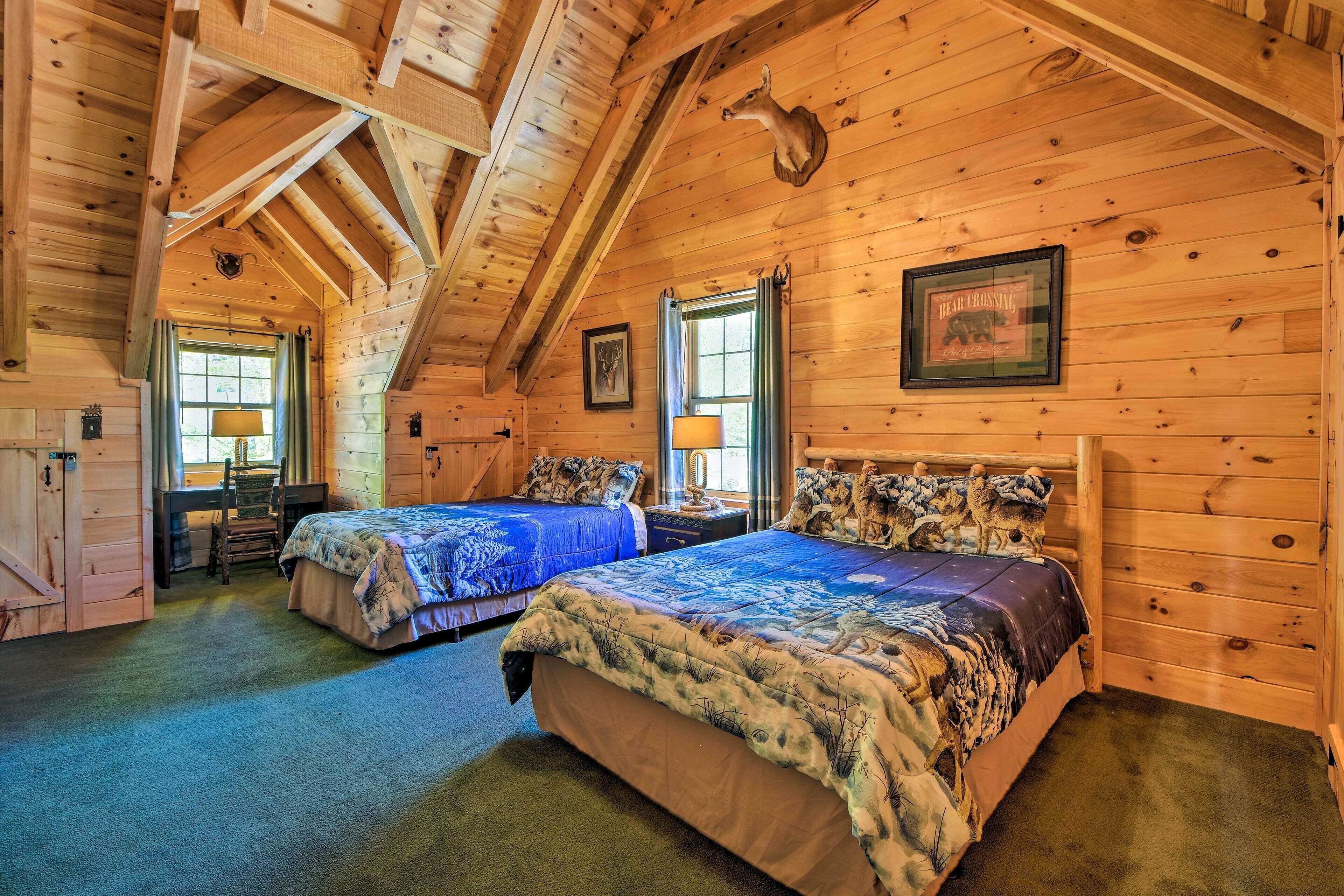 A log cabin bedroom with two beds, wooden walls, a framed picture, and a window.