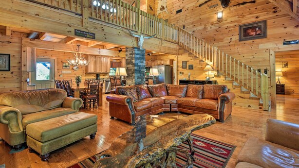 A spacious log cabin interior with a large wooden staircase, leather furniture, and a rustic decor including animal skulls and a fireplace. - Trenton Cabin w/ Hot Tub - 14 Mi to Lookout Mtn! (Trenton)