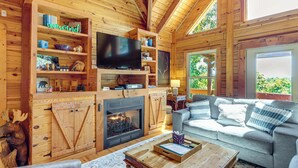 Ein gemütliches Ferienhäuschen mit Kamin, Fernseher, Holzböden und einer bequemen Sitzecke.
