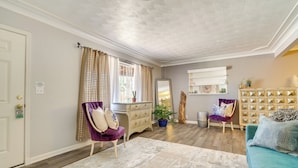 Un salon comprenant un canapé, deux fauteuils, un meuble en bois et un grand miroir.