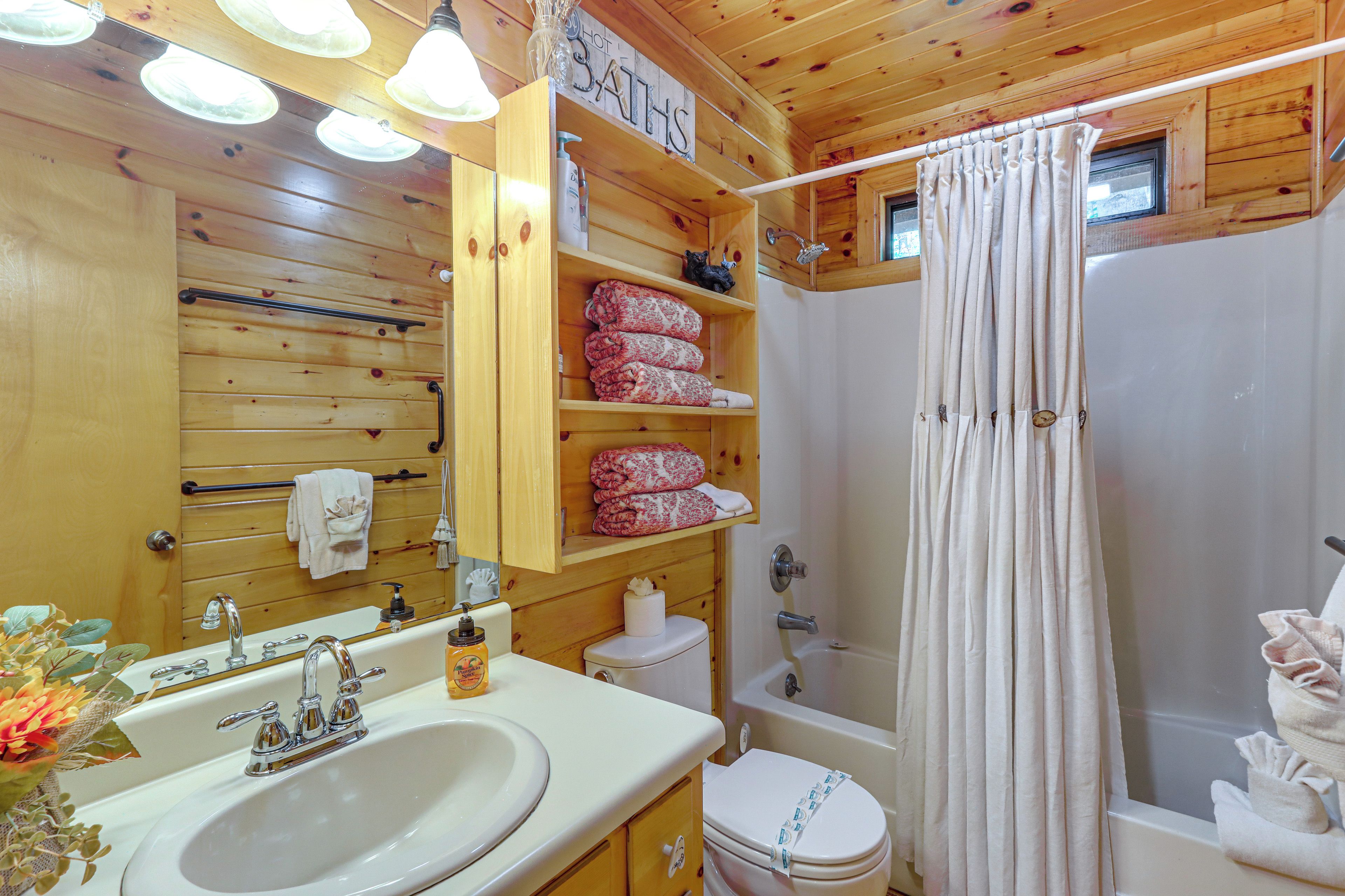A wooden cabin bathroom with a sink, toilet, and shower.