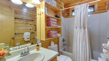 A wooden cabin bathroom with a sink, toilet, and shower.