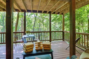 A wooden deck with a table, chairs, and a vase of sunflowers.