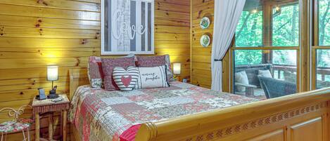 Een slaapkamer in een houten chalet, met een bed, nachtkastje, lamp en een raam met gordijnen.