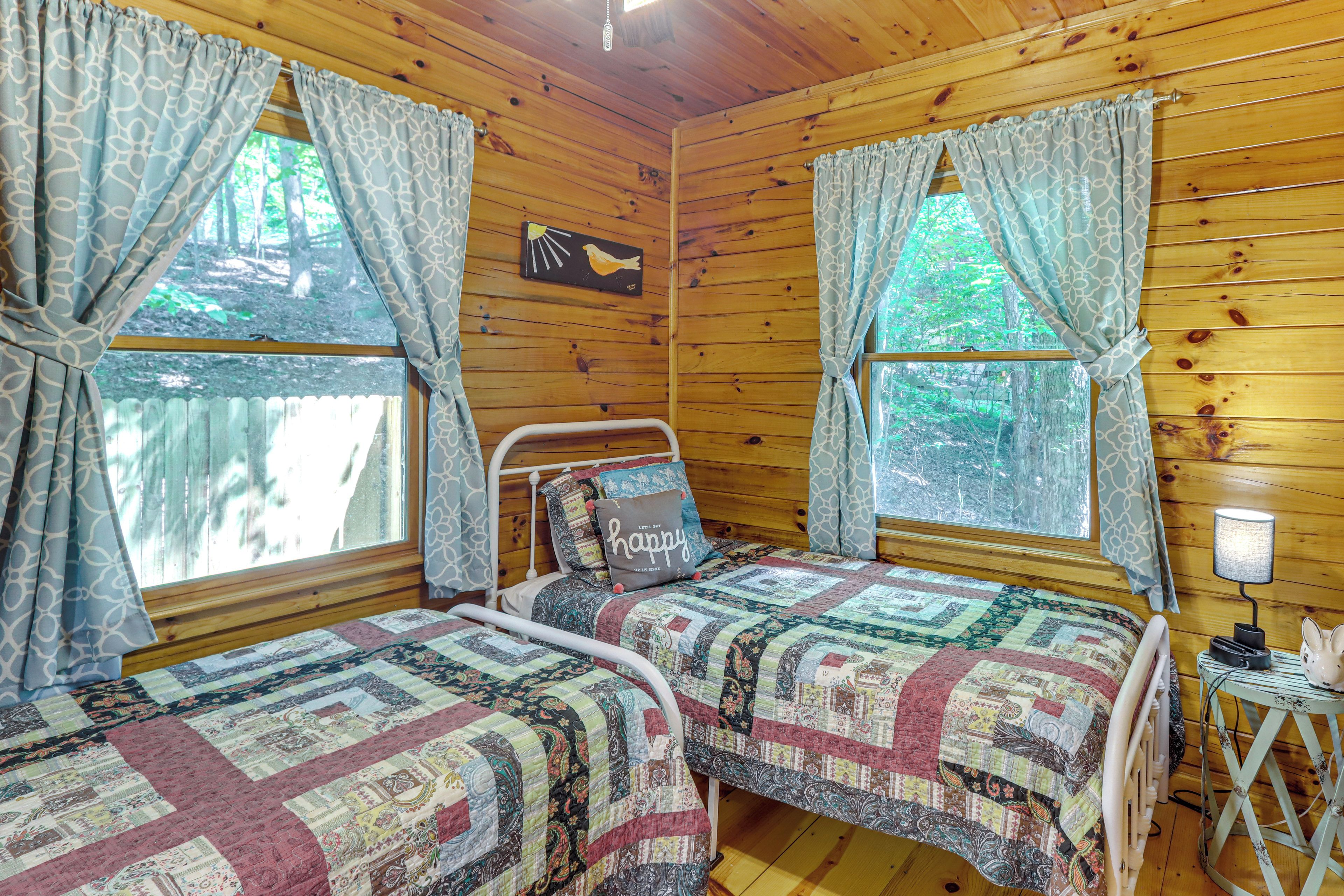 Una habitación acogedora tipo cabaña con dos camas, una mesita de noche, una lámpara y un cuadro en la pared.