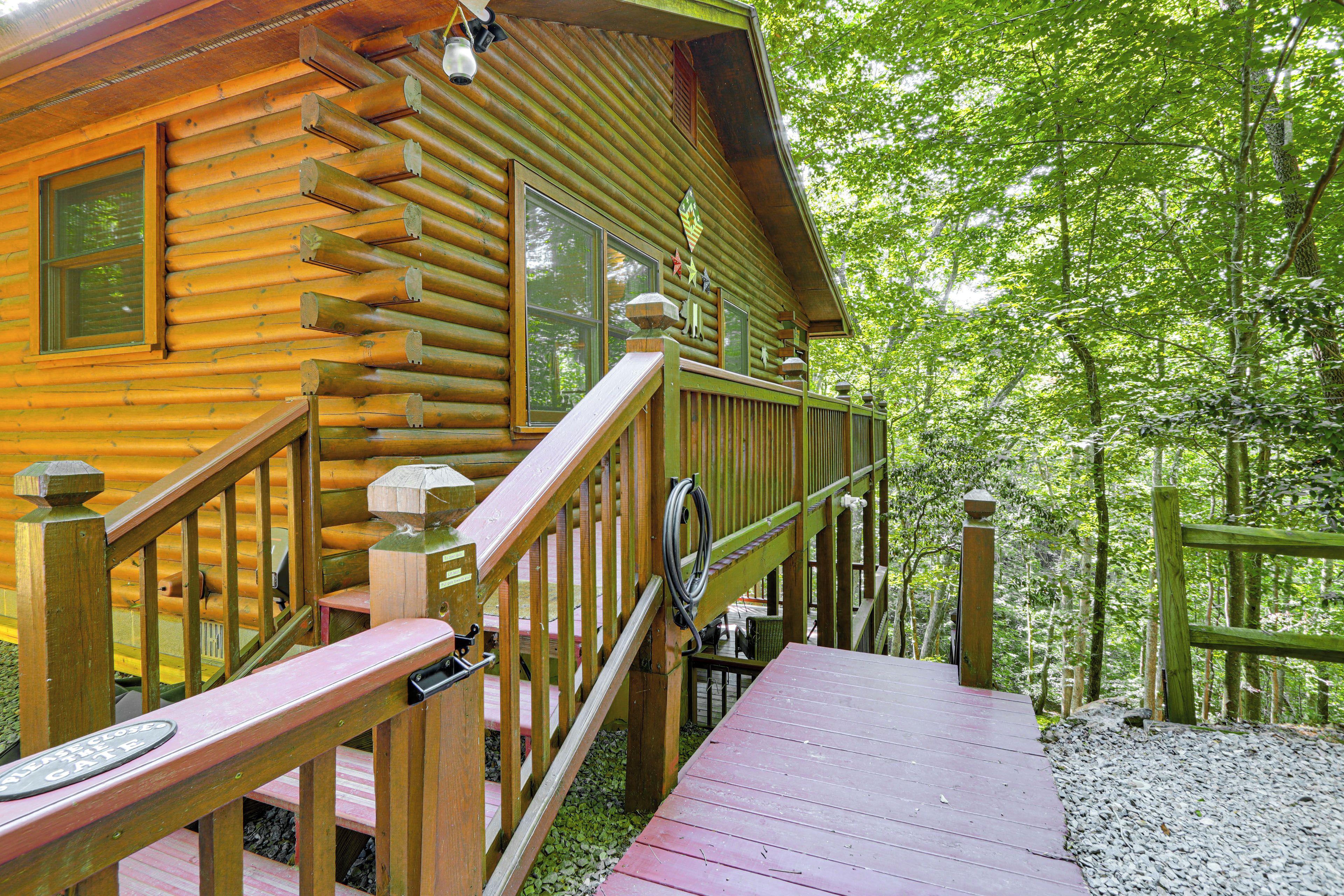 A log cabin with a wooden deck and a staircase leading to a covered porch.