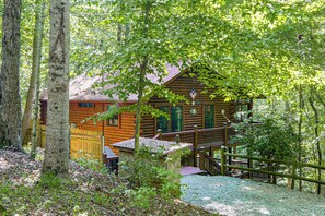 Una cabana de fusta amb un porxo, envoltada d'arbres.