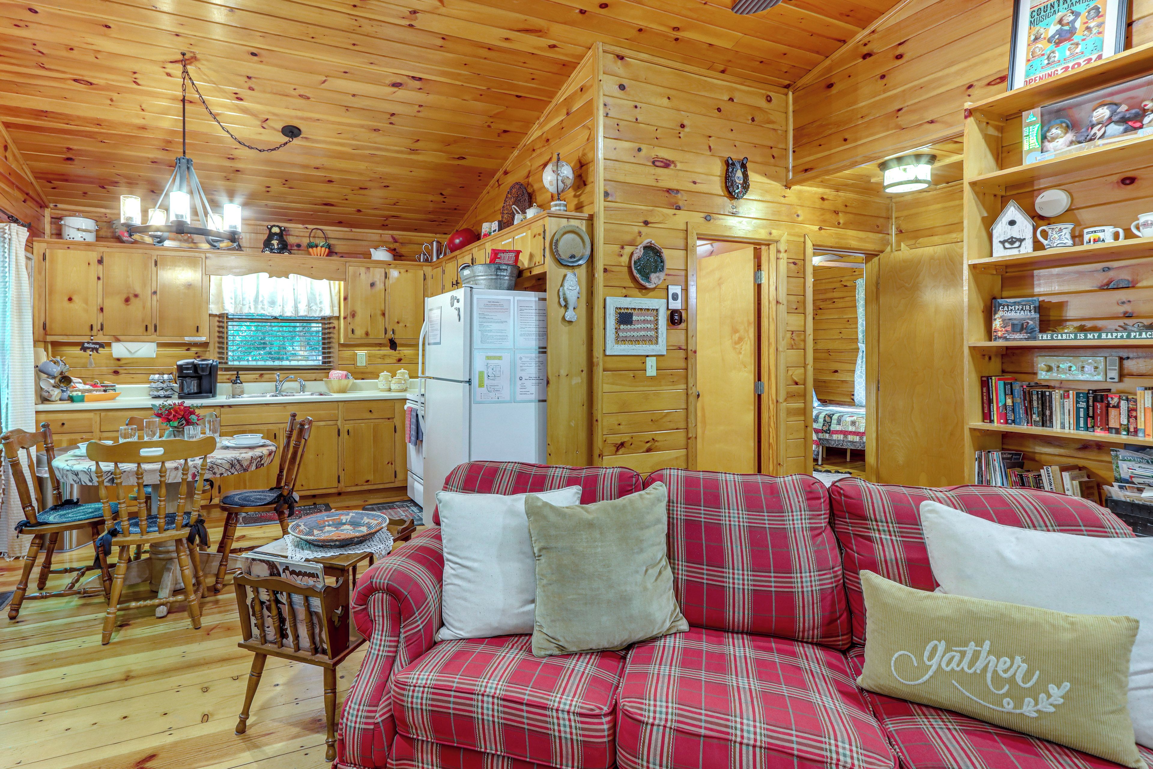 Interior de una cabaña con comedor, cocina y una sala de estar acogedora con un sofá de cuadros.