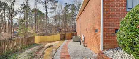 A brick building with a gravel pathway leading to a wooden fence.