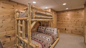 A bunk bed with a checkered bedspread and pillows featuring deer patterns, set in a room with wooden walls and ceiling. - Serene Blue Ridge Cabin ~ 3 Mi to Downtown! (Blue Ridge)
